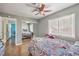 This bedroom features wood floors, a ceiling fan, a large window with blinds, and a closet with mirrored doors at 2727 Scotch Heather St, Las Vegas, NV 89142