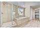 Bright bathroom featuring a glass shower, soaking tub, and views to the exterior at 3 Hilltop Crest St, Henderson, NV 89011