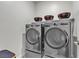 Modern laundry room with front-loading washer and dryer, complemented by decorative bowls on a shelf at 4267 E Highvale Ct, Pahrump, NV 89061