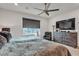 Comfortable bedroom with a ceiling fan, a large TV, a cozy chair, and natural light from a window at 4267 E Highvale Ct, Pahrump, NV 89061