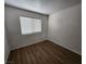 This simple, bright bedroom features a large window, wood floors, and an electrical outlet for functionality at 4610 Cannon Beach St, Las Vegas, NV 89122