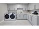 Clean laundry room featuring gray cabinets and white countertops, complete with modern washer and dryer units at 658 Dragon Peak Dr, Henderson, NV 89012