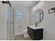 Modern bathroom featuring a glass shower, black vanity, round mirror, and stylish light fixture at 704 Berry Cir, Las Vegas, NV 89107