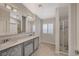 Elegant bathroom with dual sink vanity, framed mirrors, tiled flooring, and glass enclosed shower at 7992 Barntucket Ave, Las Vegas, NV 89147