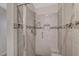 Close-up of the glass-enclosed shower featuring tiled walls, a shower bench and a decorative mosaic accent at 7992 Barntucket Ave, Las Vegas, NV 89147