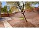 The backyard features a rockscaped hill and a concrete patio with walkway at 85 Alerion St, Las Vegas, NV 89138