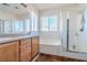 Well-lit bathroom featuring a double vanity, bathtub, enclosed shower, and a large mirror at 8523 Peaceful Dreams St, Las Vegas, NV 89139