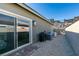 Gravel-filled backyard space featuring a sliding glass door, exterior wall lighting, and AC units at 889 Elmwood Forest Ln, Las Vegas, NV 89138