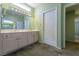 Bathroom featuring dual sinks, an oversized vanity mirror, neutral countertops, and a view into the primary bedroom at 9524 Quail Ridge Dr, Las Vegas, NV 89134