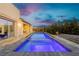 Backyard pool and patio with seating area, surrounded by lush landscaping and serene sky at dusk at 11895 Skyline Arch Ct, Las Vegas, NV 89138