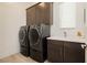 Well-equipped laundry room with modern washer and dryer units and a sink at 11895 Skyline Arch Ct, Las Vegas, NV 89138