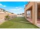 Lush backyard featuring artificial grass, bordered by a brick wall and view of the home's exterior at 1220 Earth Ct, North Las Vegas, NV 89032