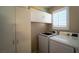 Convenient laundry room with white appliances, overhead cabinets, and a window featuring white shutters at 1300 Sand Castle Ave, Las Vegas, NV 89183