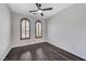 Charming bedroom featuring dark wood floors, ceiling fan, and arched windows with shutters at 1381 Robard St, Las Vegas, NV 89135