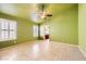 Spacious bedroom with green walls, ceiling fan, tile floors, and natural light streaming through shuttered windows at 1424 Desert Hills Dr, Las Vegas, NV 89117