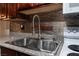 Up close view of the kitchen sink and faucet with metallic backsplash and granite countertops at 2451 N Rainbow Blvd # 2139, Las Vegas, NV 89108