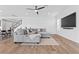 Open living area with gray sectional sofa, wood floors, and a large screen television at 3025 Merlesco Ave, Henderson, NV 89044