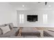 Modern living room featuring a large sofa, plush ottoman, and a wall-mounted TV with modern shutters at 3025 Merlesco Ave, Henderson, NV 89044