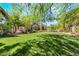 Two-story home featuring a large backyard with green grass and mature trees at 306 Treehouse Ct, Henderson, NV 89012