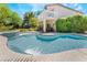 Beautiful pool and spa with waterfall feature, surrounded by lush greenery and a covered patio at 306 Treehouse Ct, Henderson, NV 89012