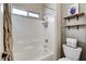 Clean white bathroom with shower-tub combo, chrome fixtures, and added shelving with storage at 387 Layla Bay St, Henderson, NV 89014