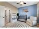 Welcoming Bedroom with blue accent wall, black crib, area rug, chair, and shelving with storage baskets at 387 Layla Bay St, Henderson, NV 89014