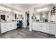 The bright bathroom features double sinks, granite countertops, white cabinetry, and gray wood-look tile flooring at 4220 Porticella Ave, North Las Vegas, NV 89084