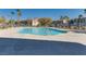 Community pool with clear water, surrounded by palm trees, bushes, and nearby residences under a clear blue sky at 4626 Lime Straight Dr, Las Vegas, NV 89115