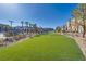 Expansive green turf in community space, lined with palm trees, bushes and residences under a clear blue sky at 4626 Lime Straight Dr, Las Vegas, NV 89115