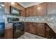 Kitchen features dark wood cabinets, tile backsplash, granite countertops, and black appliances at 4626 Lime Straight Dr, Las Vegas, NV 89115