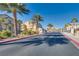 Street lined with palm trees, bushes, landscaping, and nearby residences under a clear blue sky at 4626 Lime Straight Dr, Las Vegas, NV 89115