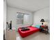 Simple bedroom with a window, red bedspread, bedside table, and tile flooring at 4716 Mountain Valley Rd, Las Vegas, NV 89121