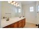 Bathroom with double vanity, wood cabinets and a large mirror with bright lighting at 500 Via Stretto Ave, Henderson, NV 89011