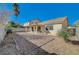 Sun-drenched backyard with gravel landscaping, covered patio, and mature plants at 5205 Mantua Ct, Las Vegas, NV 89130