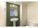 Bathroom with pedestal sink, mirror, and olive-green accent wall at 546 Foothill Cove Ln, Henderson, NV 89002