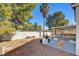 Backyard patio area with palm trees and lush landscaping with barbecue and hand-shaped chair at 6086 Shadow Oak Dr, North Las Vegas, NV 89031