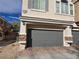 Two-car garage featuring gray door, stone accents, and brick paver driveway at 6448 Elwood Mead Ave # 103, Las Vegas, NV 89156