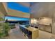 Outdoor kitchen and dining area with stainless steel grill, modern appliances, and stunning city views at 709 Dragon Peak Dr, Henderson, NV 89012