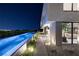 Backyard at night with large pool and modern architectural details with view through to the living room at 709 Dragon Peak Dr, Henderson, NV 89012