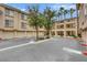 Apartment complex exterior featuring garages, lush landscaping and palm trees under blue sky at 7135 S Durango Dr # 209, Las Vegas, NV 89113