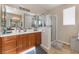 Bathroom with a glass enclosed shower, wood cabinets, double sinks, and a neutral color palette at 7321 Aspire Ct, Las Vegas, NV 89113