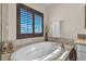 Soaking tub with marble surround, shuttered window, and decorative accents at 790 Tossa De Mar Ave, Henderson, NV 89002