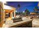 Outdoor kitchen and lounge area features a built-in barbecue, stone facade, and bar top at 790 Tossa De Mar Ave, Henderson, NV 89002