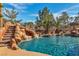 Lush backyard pool boasts a rock waterfall, exciting water slide, and ample room for lounging at 790 Tossa De Mar Ave, Henderson, NV 89002