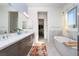 Bathroom featuring double sinks, quartz counters, a soaking tub, and a walk-in closet at 91 Alta Cascata Pl, Henderson, NV 89011