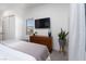 Modern bedroom featuring a mounted TV, wood dresser, and sleek white walls with neutral décor at 91 Alta Cascata Pl, Henderson, NV 89011