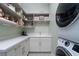 Bright laundry room with white cabinets, quartz counters, shelving, tile floor, and stacked washer/dryer at 91 Alta Cascata Pl, Henderson, NV 89011