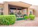 A covered patio with a seating area surrounded by lush green bushes and desert landscaping at 9300 Villa Ridge Dr, Las Vegas, NV 89134