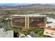 Aerial view features a modern resort hotel surrounded by desert landscape and mountain views at 10528 Meadow Mist Ave, Las Vegas, NV 89135