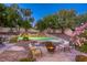 Beautiful backyard oasis with a pool, waterfall feature, firepit, and lush landscaping at 10528 Meadow Mist Ave, Las Vegas, NV 89135